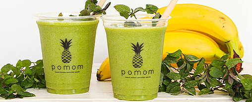 Zwei leckere grüne Smoothies der Firma Pomom stehen vor Bananen und Spinat und machen Appetit auf mehr Gastronomie im Freizeitpark.